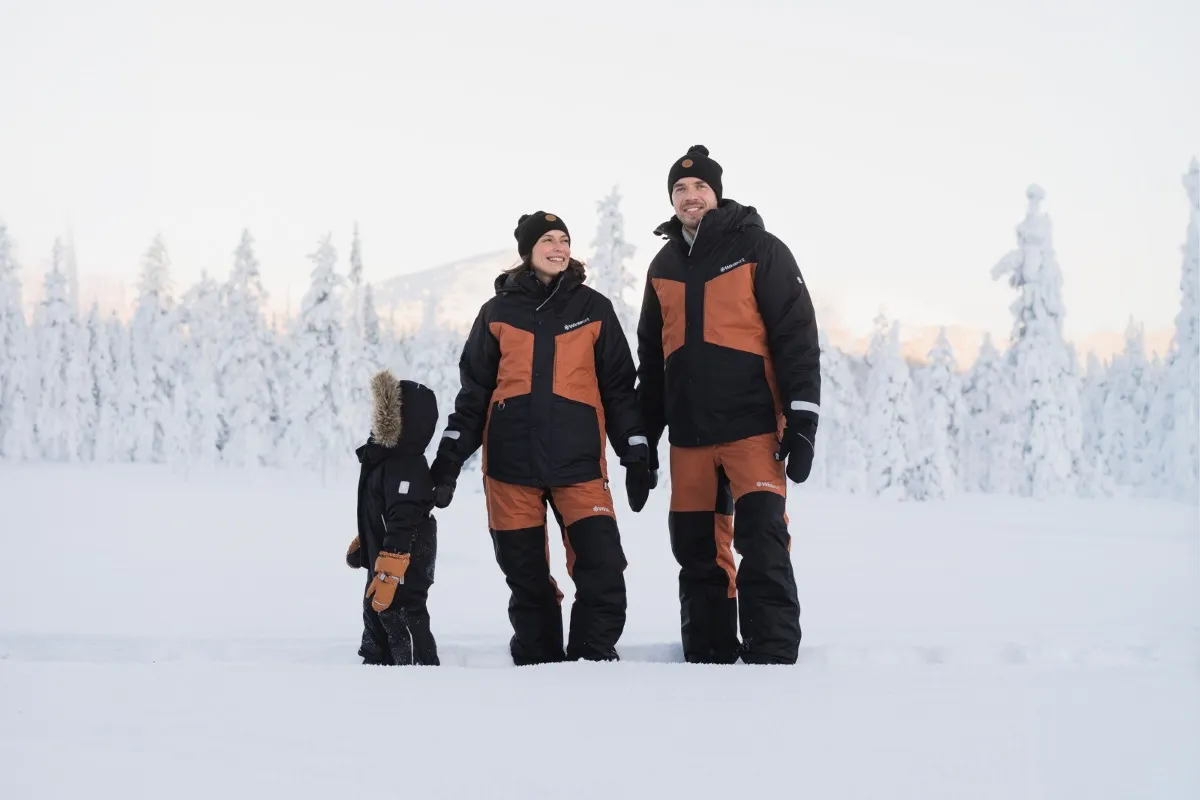 Family in rental winter clothing in the snowy forest in Levi